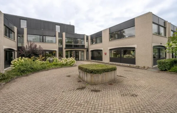 Moderne kantoorvilla aan de Burgemeester Verderlaan met beige bakstenen gevel, zwarte kozijnen en een groene binnentuin.